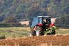 Tractor ploughing a field with a forest in the distance