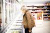 Mature woman in supermarket, looking in freezer cabinet - stock photo