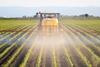 tractor spraying field with pesticides