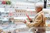 Woman choosing fresh milk and using smart phone to check the nutrition label on the pot - Getty Images