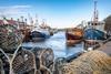 Fishing boats and trawlers docked beside lobster pots in Eyemouth Harbour, Scotland - stock photo