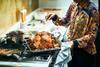 woman basting turkey on top of oven