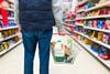 Shopper holding baskey in supermarket aisle