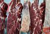 Rows of raw beef hanging in a butcher shop, ready to be cut and sold - Getty Images