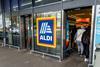 he entrance and exit of a branch of Aldi grocery supermarket with the company name sign and logo in the middle