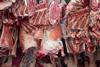 Meat being delivered to a butcher hanging from hooks