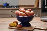 A colander of red and white potatoes on a kitchen countertop