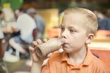 A picture of a young boy drinking a milkshake out of a bottle