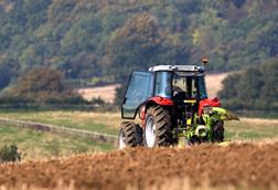 Tractor ploughing a field with a forest in the distance