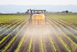 tractor spraying field with pesticides
