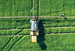 Tractor sprays fertilizer and water on a green fields of East Sussex, UK - stock photo