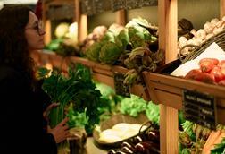 Woman selecting fresh vegetables at a market stall filled with diverse produce - stock photo - Getty Images