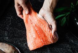Close-up of a chef preparing fresh salmon fillet in kitchen