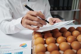 A businessman checks eggs at a work table in a factory, ensuring cleanliness and freshness