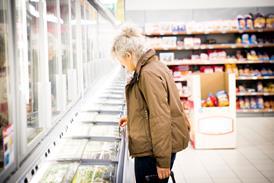 Mature woman in supermarket, looking in freezer cabinet - stock photo
