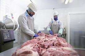 Two men working in a meat processing factory