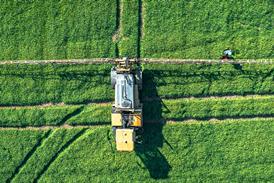 Tractor sprays fertilizer and water on a green fields of East Sussex, UK - stock photo