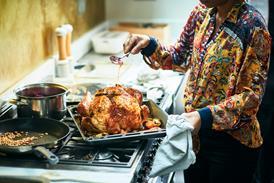 woman basting turkey on top of oven
