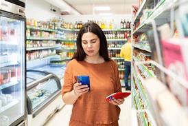 Woman using phone standing in the supermarket - stock photo