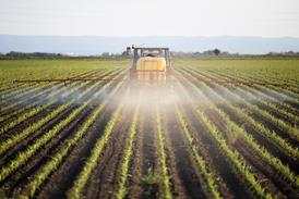 tractor spraying field with pesticides