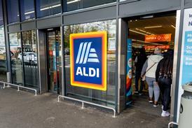 he entrance and exit of a branch of Aldi grocery supermarket with the company name sign and logo in the middle