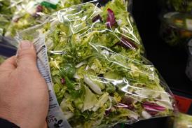 a hand holding a bag of salad