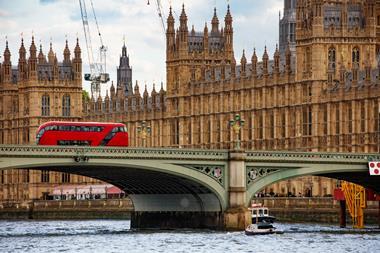 Red double-decker bus crossing Westminster Bridge in London UK - Getty