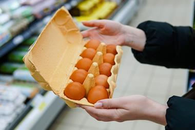 Woman chooses chicken eggs in a grocery store. Close up - Getty Images