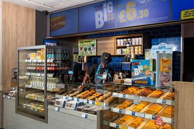 Greggs - A staff member arranges products behind a counter at a Bitesize Greggs outlet