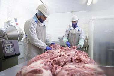 Two men working in a meat processing factory