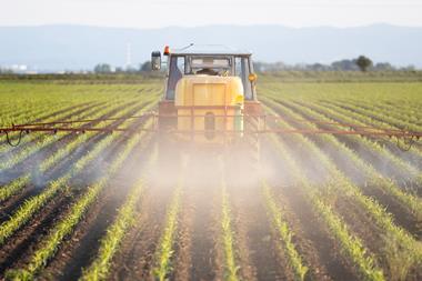 tractor spraying field with pesticides