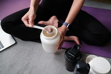 Woman scooping whey powder into shake