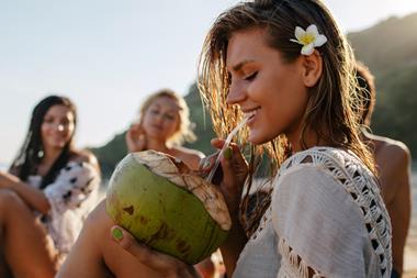 Young woman drinking coconut water from a coconut