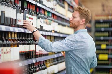 Man choosing wine bottle from shelf