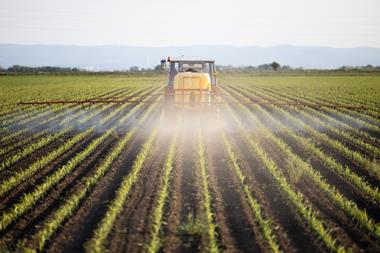 tractor spraying field with pesticides