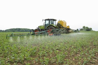 Tractor in field spraying crop - stock photo - Getty