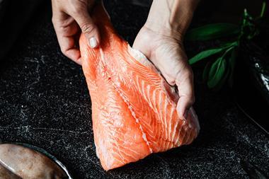 Close-up of a chef preparing fresh salmon fillet in kitchen