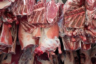Meat being delivered to a butcher hanging from hooks