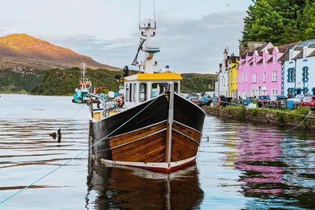 Fishing boat moored in the colorful harbor of portree, isle of skye, scotland - Getty Images
