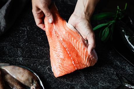 Close-up of a chef preparing fresh salmon fillet in kitchen