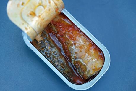 Opened tin of sardines in tomato sauce on a blue plate - Getty