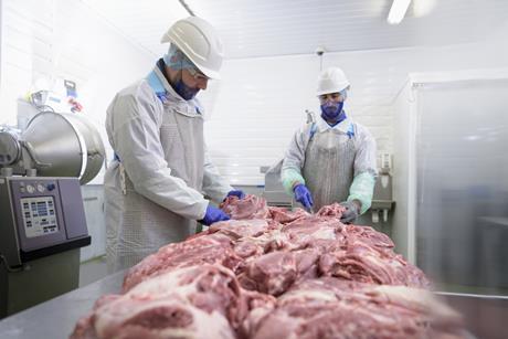 Two men working in a meat processing factory