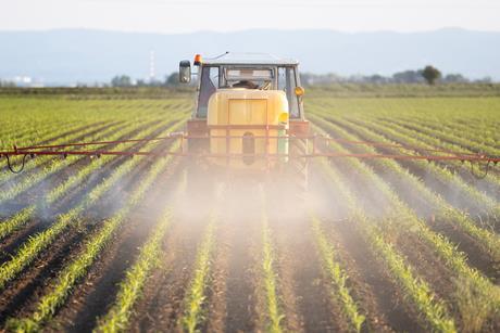 tractor spraying field with pesticides