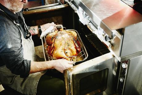 Man pulling cooked turkey out of oven - stock photo - Getty Images