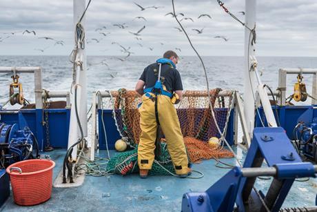 Fisherman inspecting trawl net on research ship