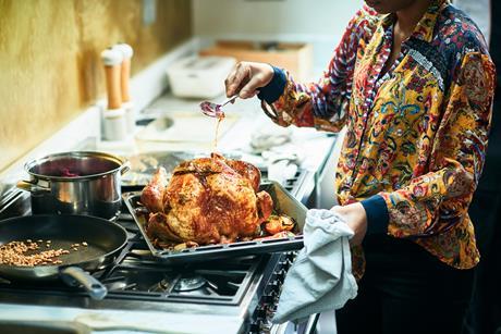 woman basting turkey on top of oven