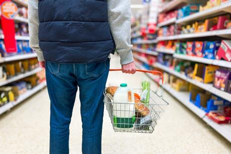 Shopper holding baskey in supermarket aisle