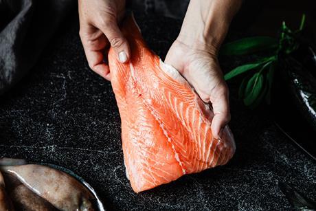 Close-up of a chef preparing fresh salmon fillet in kitchen
