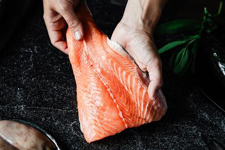 Close-up of a chef preparing fresh salmon fillet in kitchen