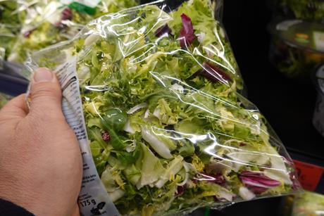 a hand holding a bag of salad